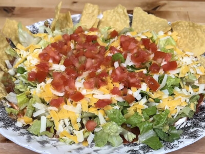 Easy 7 layer taco dip recipe loaded with creamy layers, melty cheese, fresh toppings, and bold Tex-Mex flavor—an easy party dip everyone will devour!