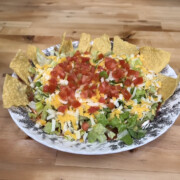 Easy 7 layer taco dip recipe loaded with creamy layers, melty cheese, fresh toppings, and bold Tex-Mex flavor—an easy party dip everyone will devour!