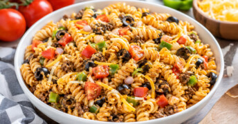 This easy taco pasta salad recipe makes a quick one-dish meal that's perfect for busy summer nights, potlucks, picnics, or easy lunches. Tender pasta, seasoned meat, fresh vegetables, cheese, and a tangy Catalina dressing come together for a family-friendly meal that's also a great way to use leftover meat and veggies.