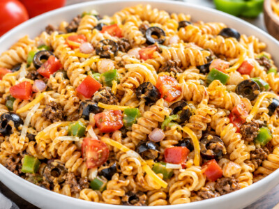 This easy taco pasta salad recipe makes a quick one-dish meal that's perfect for busy summer nights, potlucks, picnics, or easy lunches. Tender pasta, seasoned meat, fresh vegetables, cheese, and a tangy Catalina dressing come together for a family-friendly meal that's also a great way to use leftover meat and veggies.